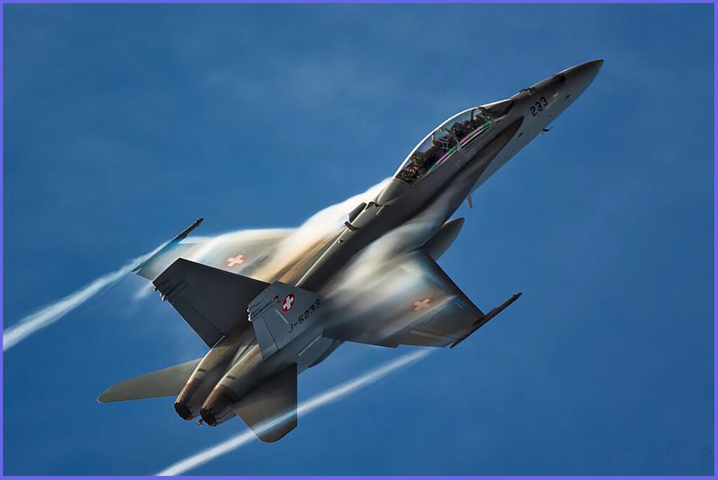 An F-18 with condensation in the cores of its wingtip vortices and on the top of its wings.